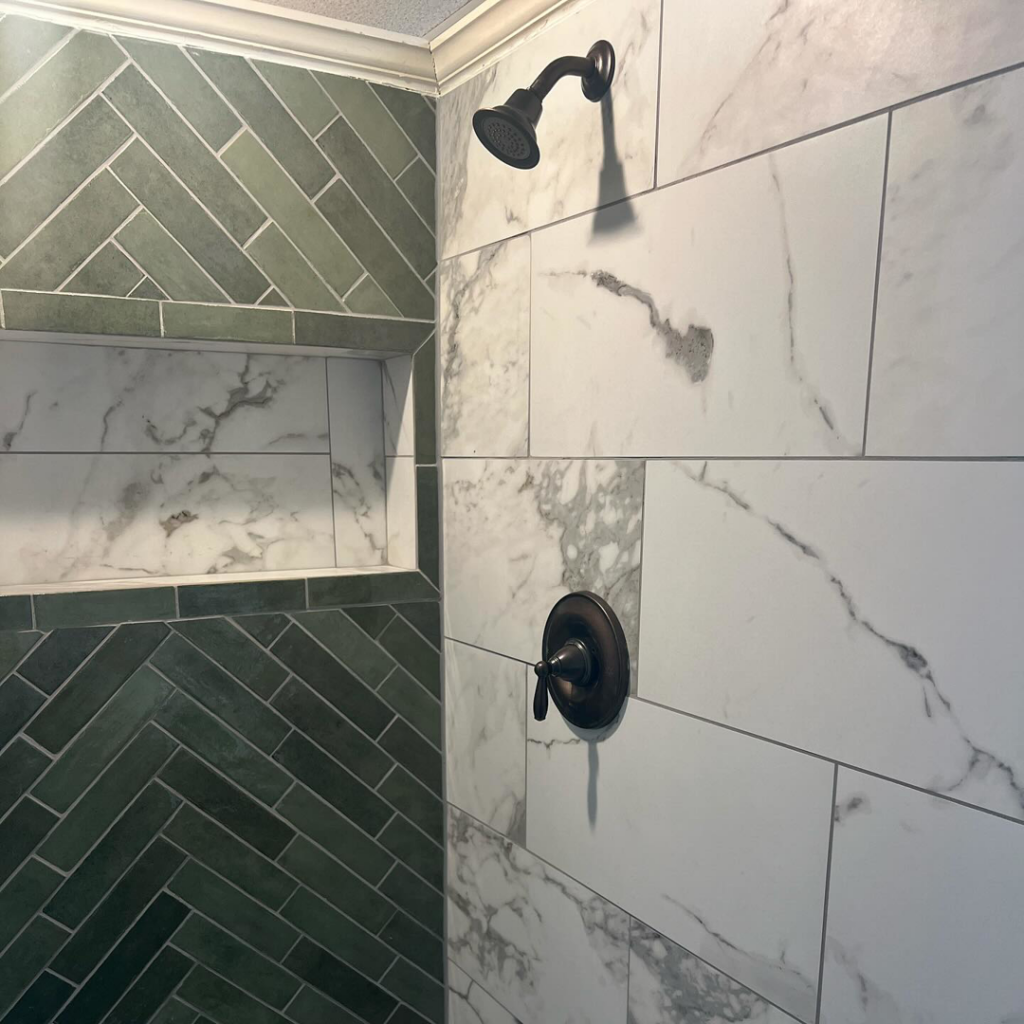 A modern tiled shower with dark bronze fixtures and green herringbone tiles by City Home Improvement Inc in Portland, OR.