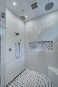 A modern tiled shower installation with multiple showerheads and glass enclosure by Ranney Blair Weidmann in Roswell, GA.