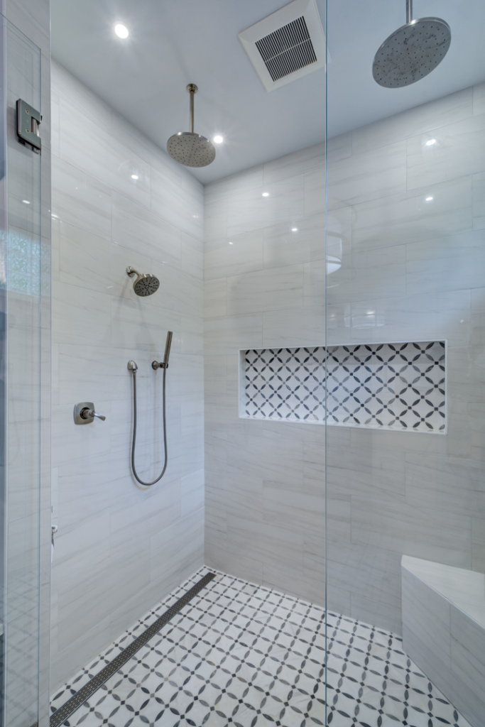 A modern tiled shower installation with multiple showerheads and glass enclosure by Ranney Blair Weidmann in Roswell, GA.