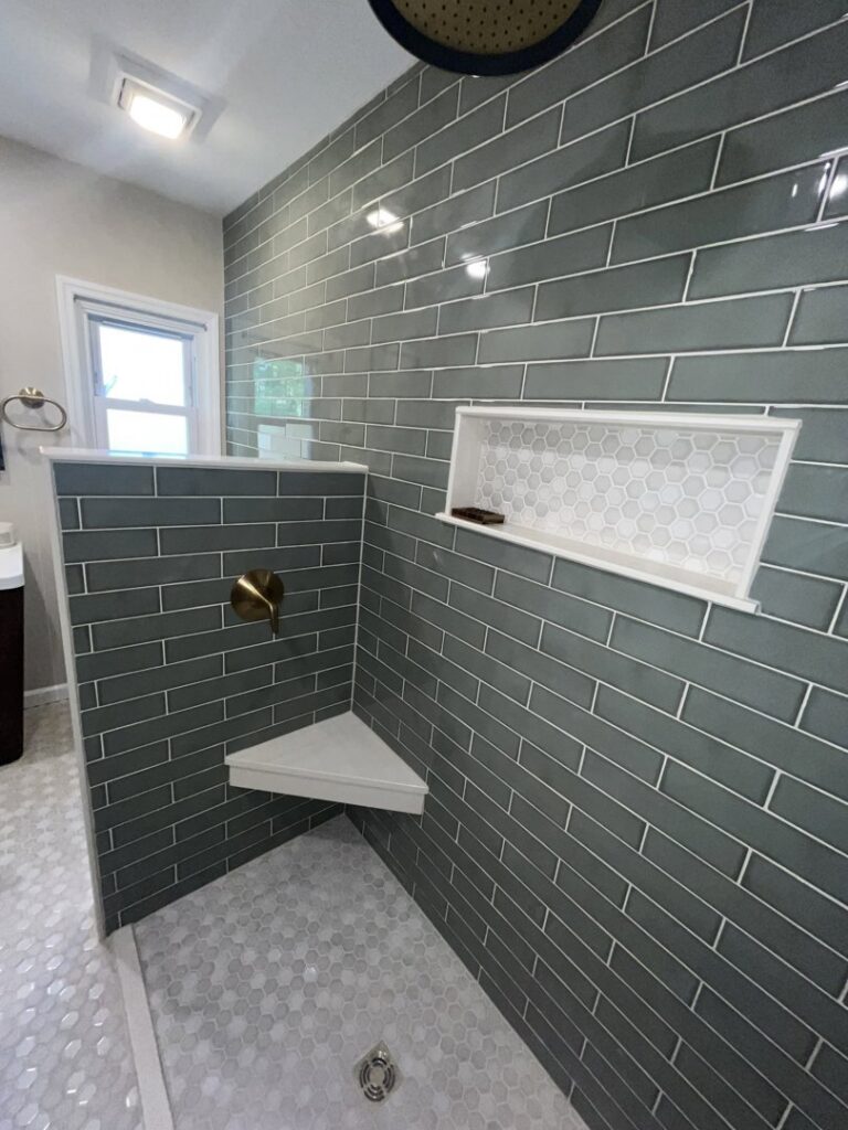 A modern walk-in shower with green subway tiles and a built-in shelf installed by Stanley Contracting in Whiting, NJ