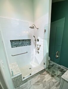 A modern walk-in shower with white subway tiles, a decorative niche, and a built-in bench by Pluff Contractors LLC in Lancaster, PA.