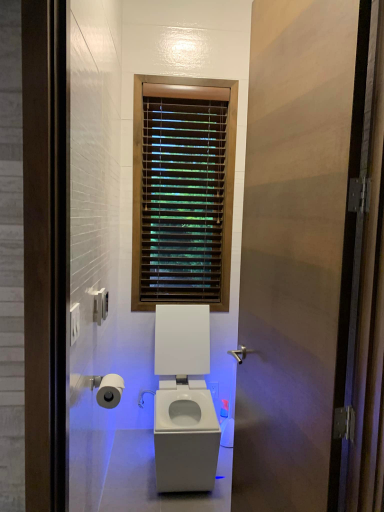 A modern toilet room installation with white tiled walls and smart toilet by Andalex Construction LLC in Gresham, OR.