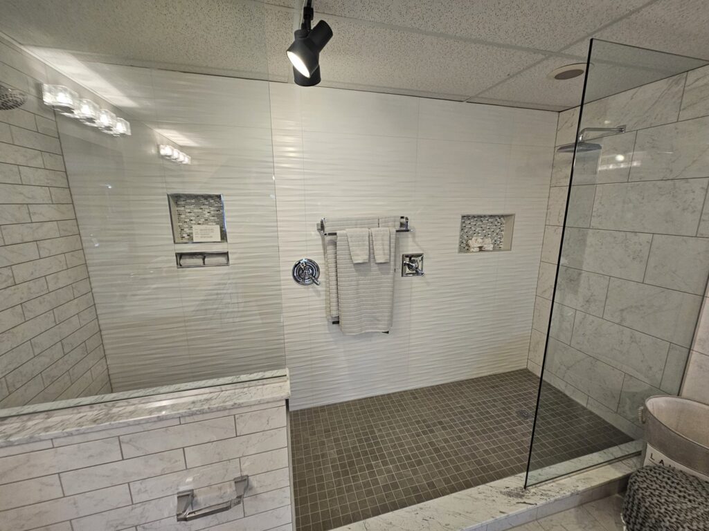 A modern bathroom featuring a spacious walk-in shower with white textured tiles by Creative Building & Remodeling in Warren, MI