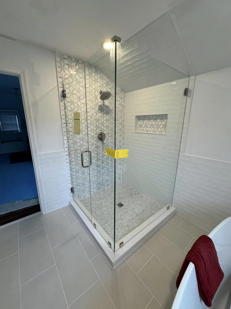 A modern walk-in shower with a glass enclosure and patterned tiles by A&L Tile LLC in San Diego, CA