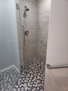 A modern walk-in shower featuring grey tiled walls and a hexagonal tiled floor, installed by Jedi Bldrs in Colorado Springs, CO.