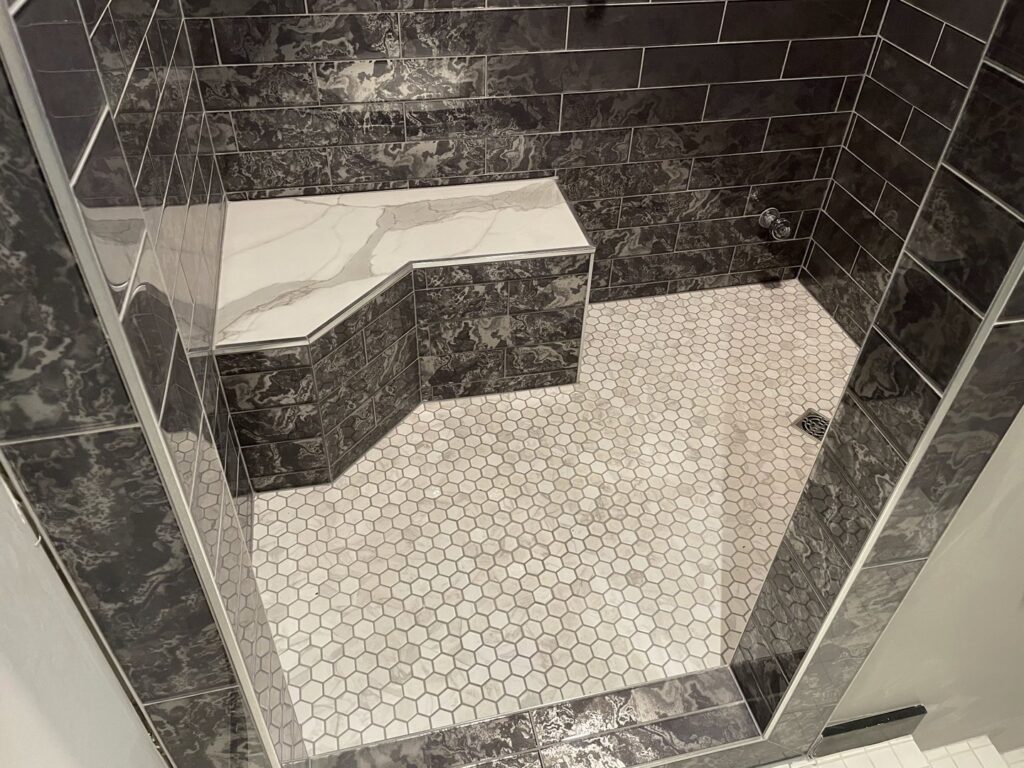 A modern walk-in shower with dark gray and white tiles installed by E.L. Construction in Kansas City, MO.