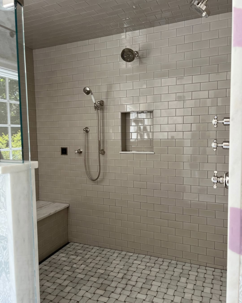A modern walk-in shower with subway tiles and mosaic floor installed by Kevin Cradock Builders in Boston, MA.