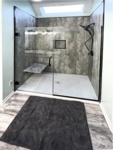 A modern walk-in shower with textured walls and glass door installed by Thrive Homes, LLC in Olathe, KS.