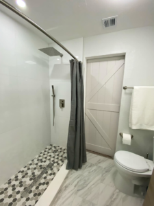 A modern walk-in shower renovation with rain showerhead and hexagonal tiles by Property Solutions Network, Llc in Hialeah, FL