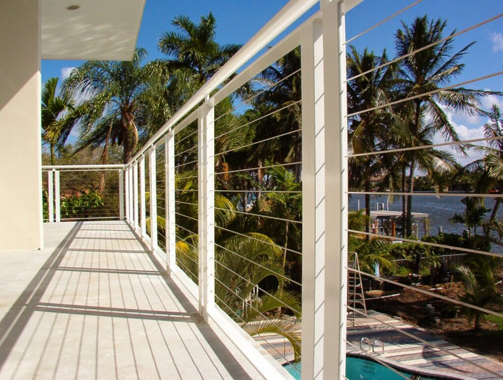 Modern white cable balcony railing installed by Xclusive Fence And Rails Inc. in Miami, FL, overlooking a pool.