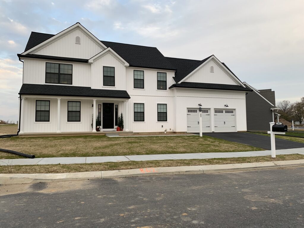 A modern farmhouse-style new construction home with white siding and black windows by Lancaster Home Builders in Lancaster, PA.