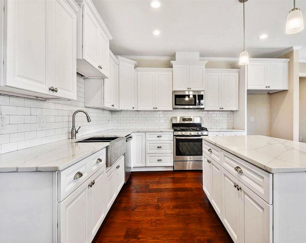A modern white kitchen remodel with subway tile backsplash and stainless steel appliances by Regal Remodelers in Baton Rouge, LA.