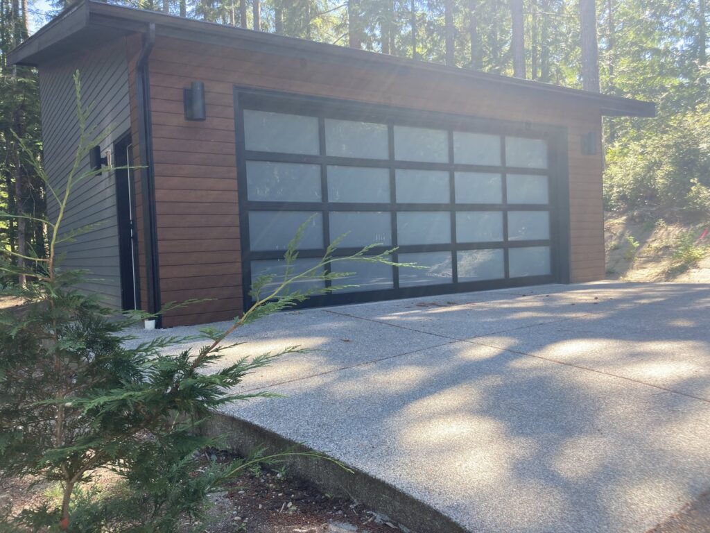A modern garage with wood siding and a frosted glass panel door by Garages Etc in Tacoma, WA