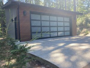 A modern garage with wood siding and a frosted glass panel door by Garages Etc in Tacoma, WA