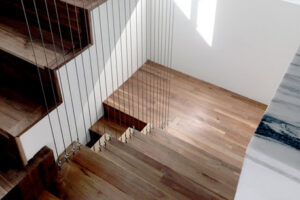 A modern wooden staircase with sleek cable railings, installed by Kaleidoscope Design Build in Houston, TX.