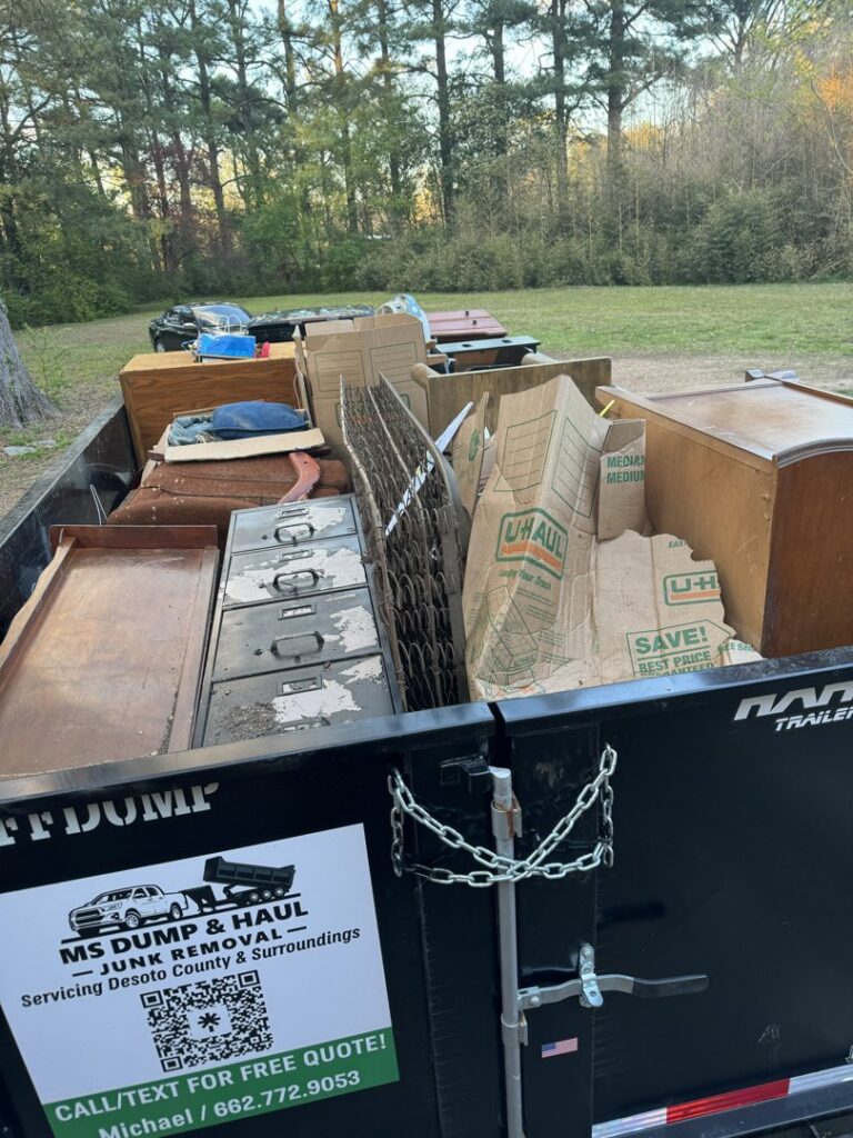 An MS Dump & Haul branded dumpster completely full of various household junk and debris in Hernando, MS.