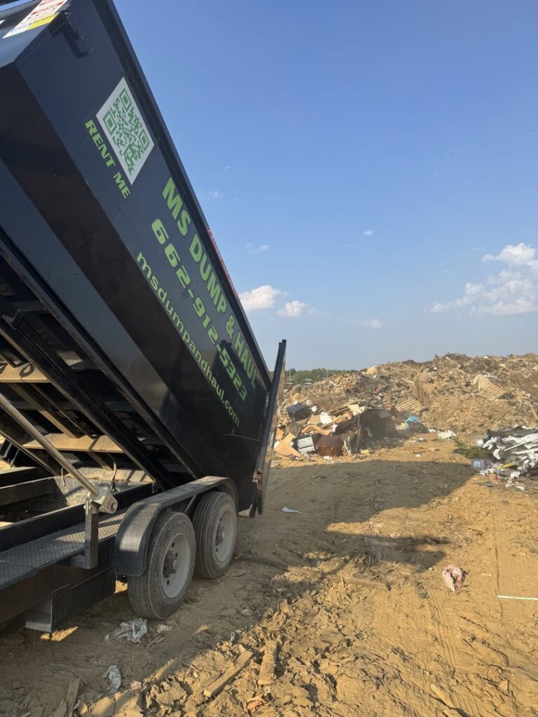 An MS Dump & Haul dumpster being unloaded at a landfill or large debris pile in Hernando, MS.