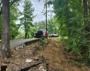 An MS Dump & Haul truck, dumpster trailer, and skid steer loader set up at a junk removal job site in Hernando, MS.