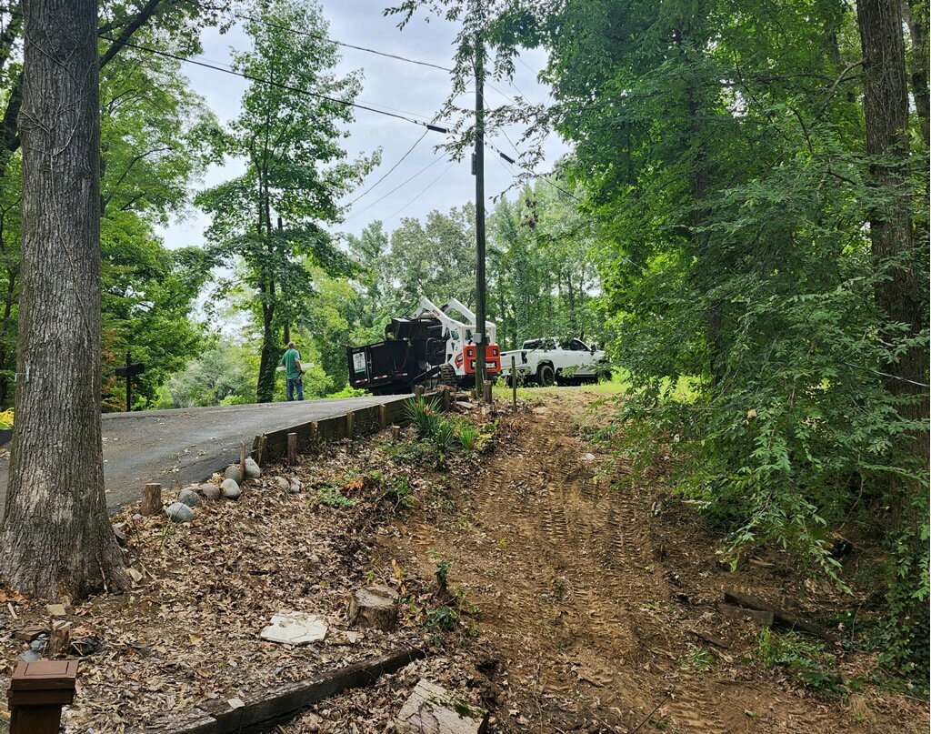 An MS Dump & Haul truck, dumpster trailer, and skid steer loader set up at a junk removal job site in Hernando, MS.