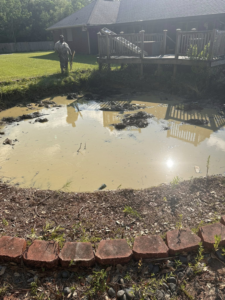 A muddy, empty pool area requiring cleanup and junk removal by Weekly Waste Solutions in Jackson, MS.