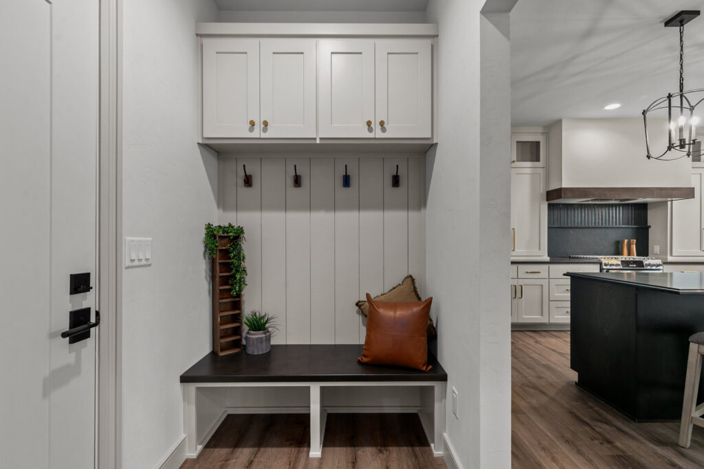 A newly installed mudroom bench with coat hooks and overhead cabinets by Mark Winter Homes in Appleton, WI.