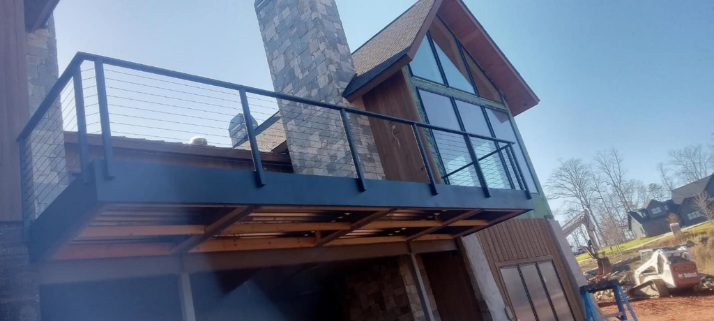 A multi-level deck with black metal railing on a house under construction by American Cable & Rigging in Mills River, NC.