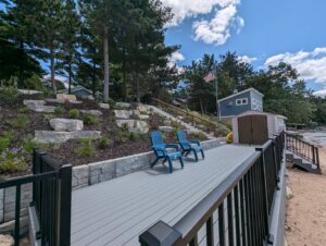 A multi-level deck and dock area with stone retaining walls and stairs leading to the water, built by Wildflower Landscapers LLC in Larsen, WI