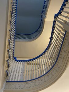 View looking up a multi-story staircase with balusters taped for painting by S-G General Contracting LLC in Philadelphia, PA.