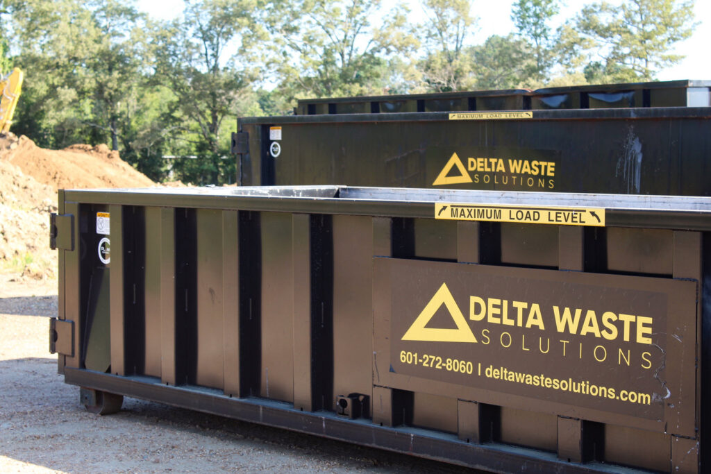 Several black Delta Waste Solutions dumpsters lined up, ready for junk removal services in Hattiesburg, MS.