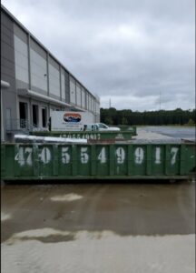 Multiple green IEG Disposal roll-off dumpsters outside a commercial building for large-scale junk removal in Canton, GA.