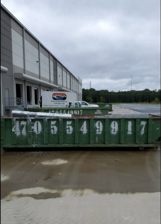 Multiple green IEG Disposal roll-off dumpsters outside a commercial building for large-scale junk removal in Canton, GA.
