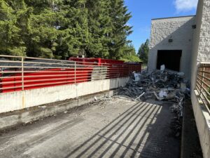 Multiple red dumpsters from Cascade Container and Recycling with a pile of metal debris at a commercial site in Seattle, WA.
