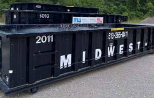 Multiple black Midwest Containers dumpsters, one with a service list, ready for junk removal in Cincinnati, OH.