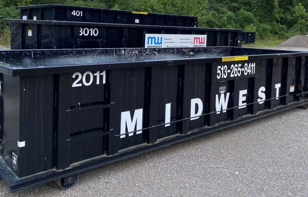 Multiple black Midwest Containers dumpsters, one with a service list, ready for junk removal in Cincinnati, OH.