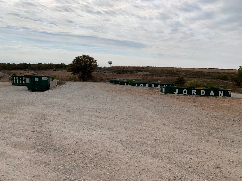 Multiple green dumpsters branded 'JORDAN' lined up on a gravel lot, indicating services by Jordan Disposal, LLC in Galena, KS.