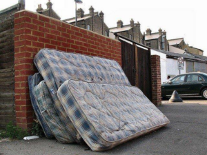 Multiple plaid mattresses leaning against a brick wall, awaiting disposal by Omaha junk Removal and Hauling Service in Omaha, NE.