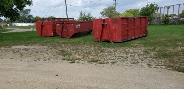 Multiple red roll-off dumpsters from SS ROLL OFF Dumpsters lined up for general junk removal in Rockford, IL.