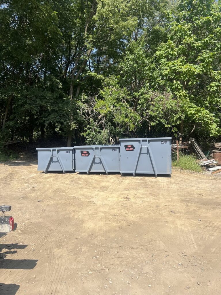 Multiple empty grey roll-off dumpsters of various sizes lined up, available from Iowa Roll Off in Ankeny, IA.
