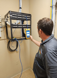 A technician testing network cables connected to a patch panel, a service offered by Lowcountry Current LLC in Moncks Corner, SC.