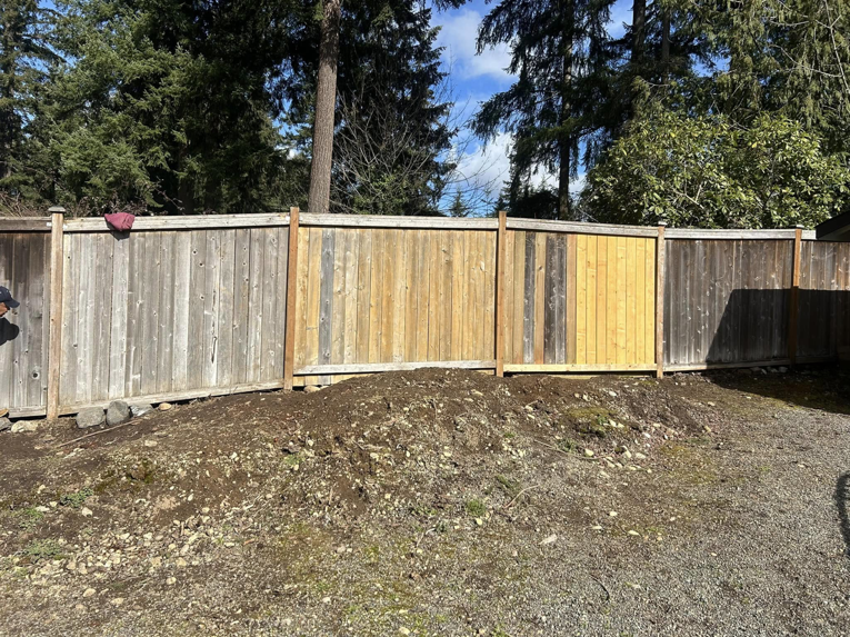 A wooden fence showing a mix of new and old sections after repair by HandyMan Shocks in Tacoma, WA.