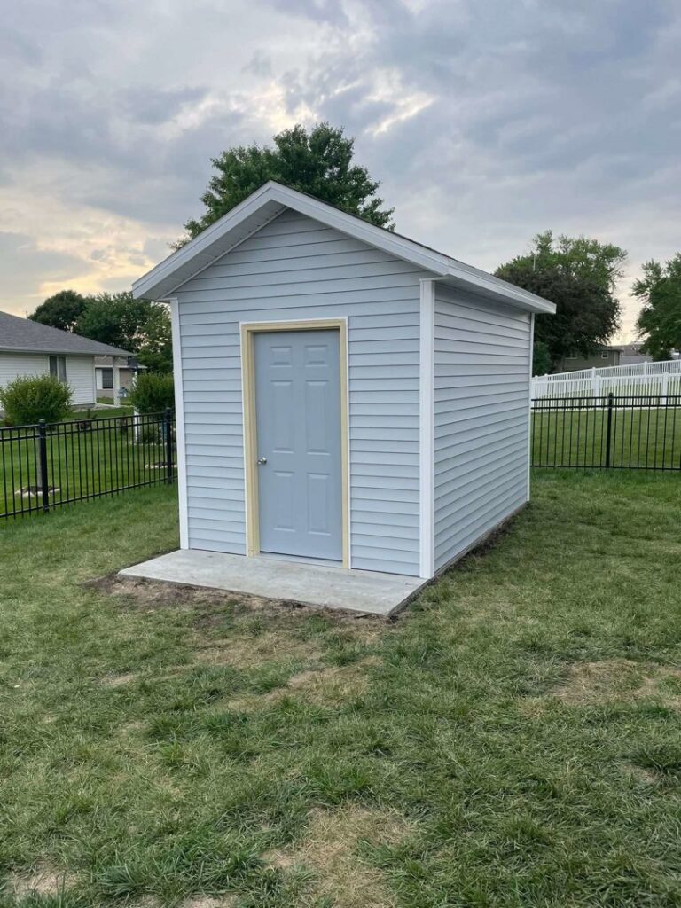 A newly constructed backyard storage shed with light blue siding by CJP Construction handyman services in Pierce, NE.