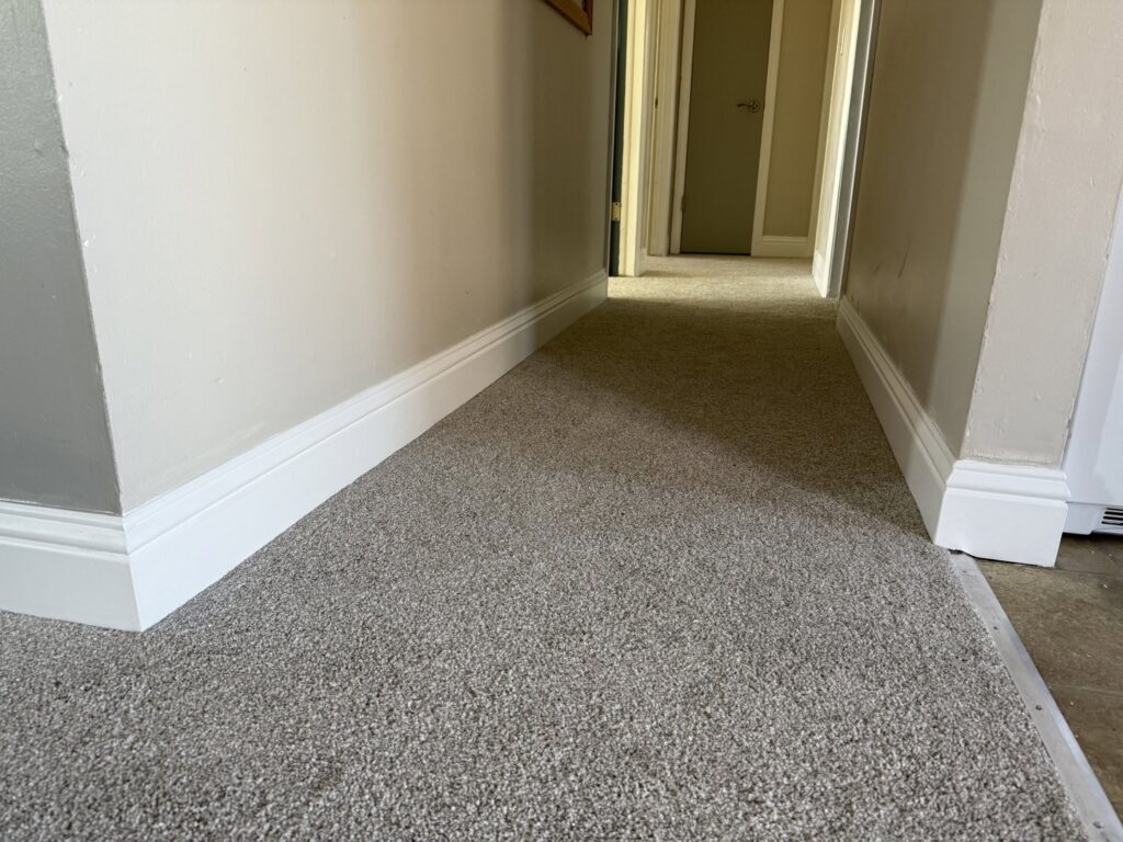 New baseboards installed in a hallway with new carpet by Max Maintenance in Twin Falls, ID.