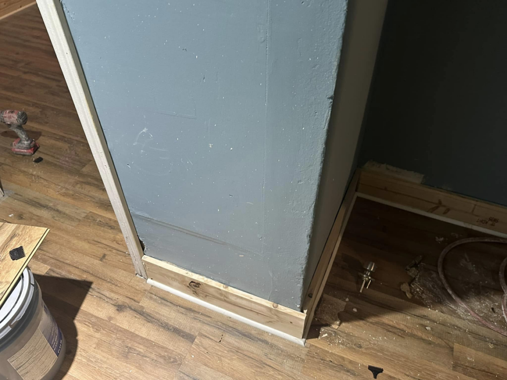 Close-up of new baseboards and wood-look flooring installation by Snell & Sons Construction LLC in Mobile, AL.