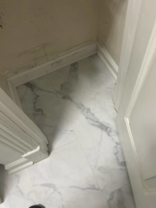 Newly installed marble-look floor tiles and baseboards in a bathroom, showcasing work by Tackett's Pro Trade Services in Berea, KY.
