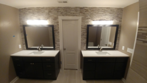 A newly renovated bathroom featuring dual vanities, mirrors, and a stylish tiled accent wall by J & J Home Improvements, LLC in Franklin, TN.