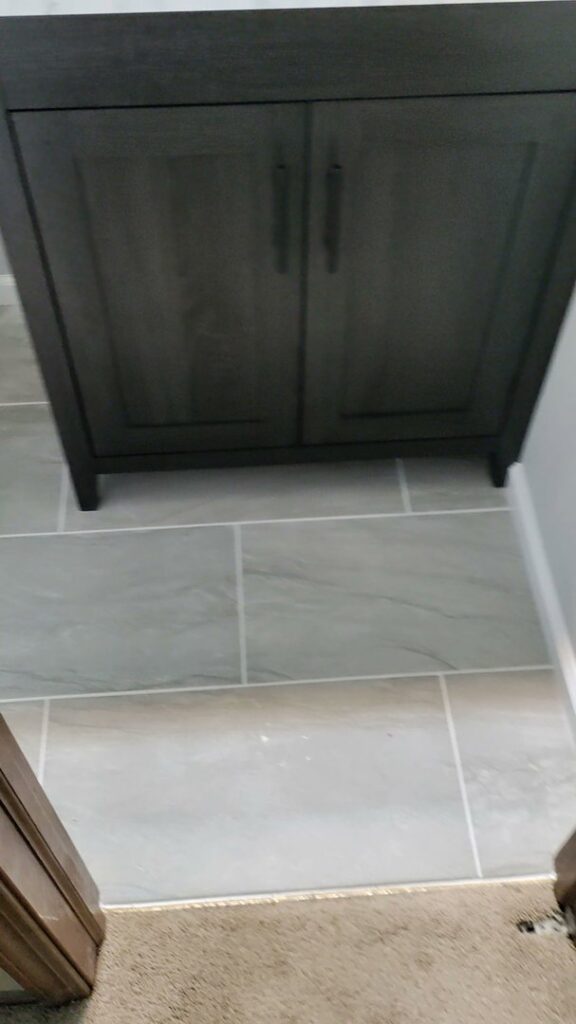 A newly installed bathroom vanity and modern tile floor, representing a completed renovation by Homefix Lawrence in Lawrence, KS.