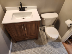 A newly installed bathroom vanity, sink, and toilet with herringbone tile flooring by SG Service, LLC in Lincoln, NE