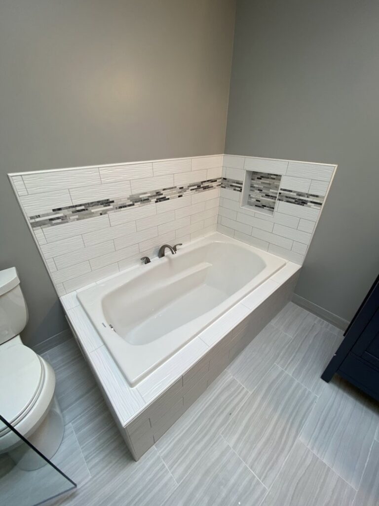A newly installed bathtub with modern tile surround and niche by Grizzly Renovations in Naperville, IL