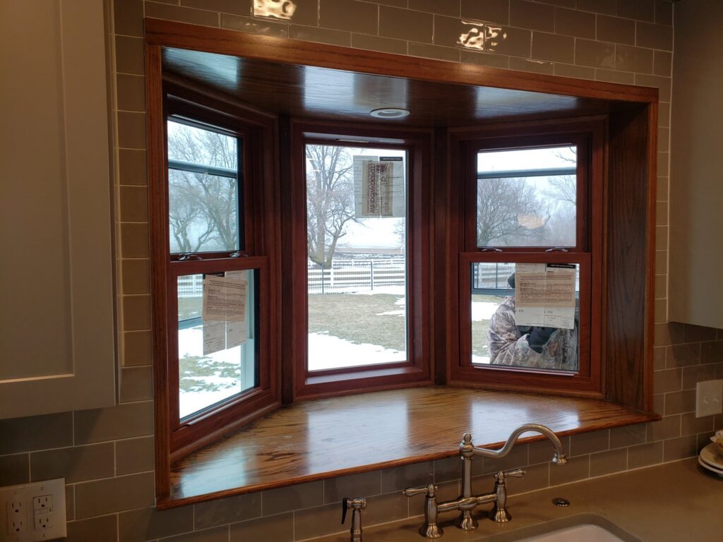 A newly installed bay window with wooden trim and a countertop in a kitchen by Rosewalls Handyman & Remodeling in Des Moines, IA.