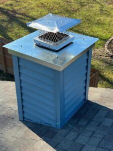 A newly installed blue chimney chase cover with a shiny metal cap on a roof by Keep It Simple Construction LLC in Woodburn, IN.